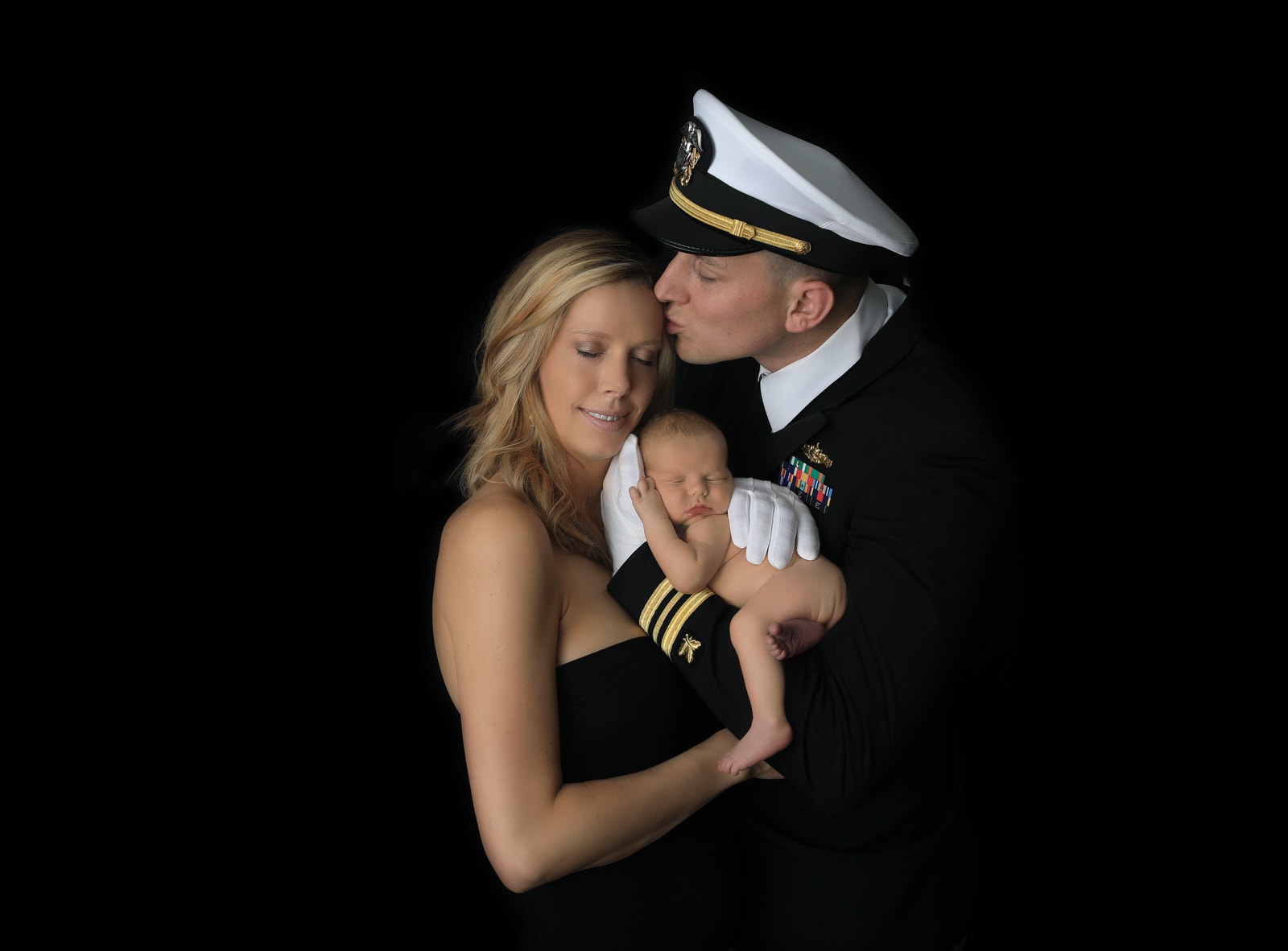 US navy dad poses in unifrom with newborn baby boy and mom at newborn photography session