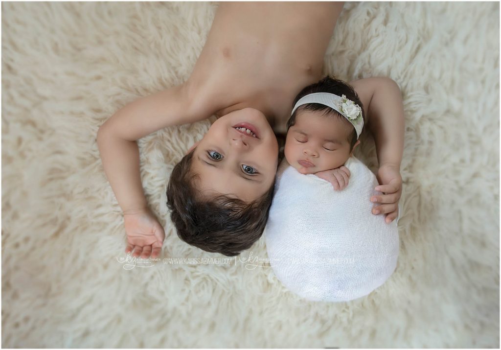 big brother poses with his baby sister during photo session with camp hill newborn photographer