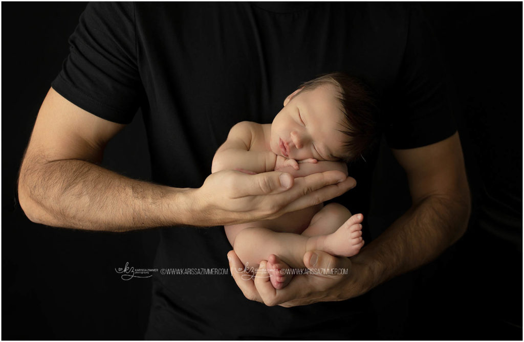 newborn baby boy posed in dads hands by camp hill newborn photographer karissa zimmer photography