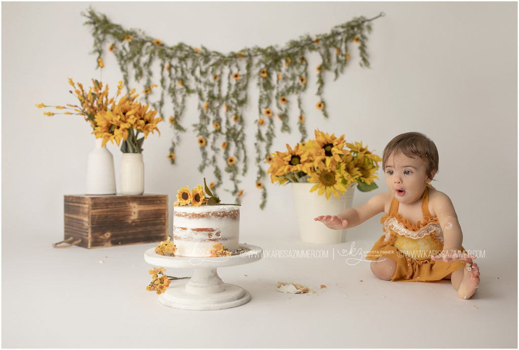 Baby girl gets excited to eat cake at her first birthday photography session with Karissa Zimmer Photography