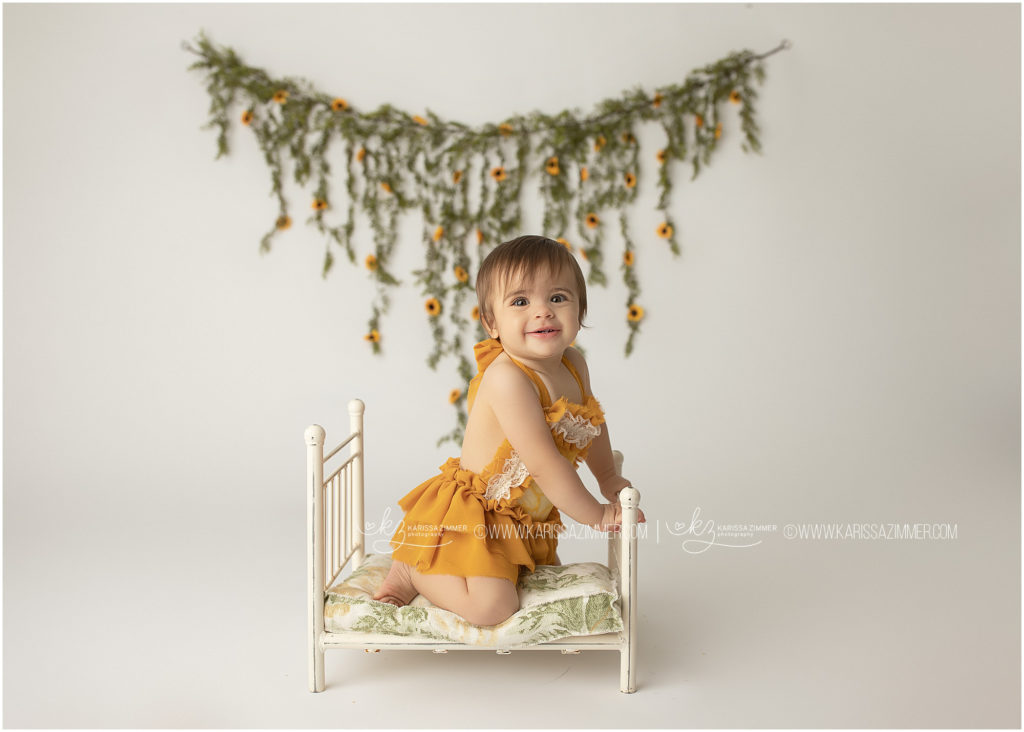 baby girl wears yellow and smiles at her camp hill first birthday photography session