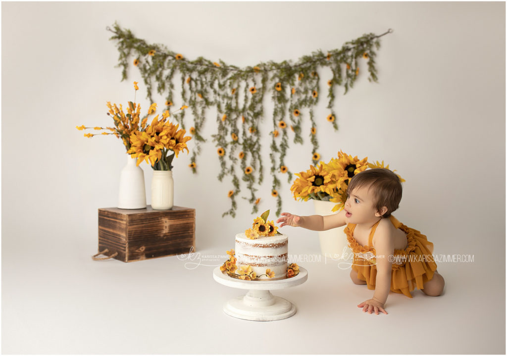 baby girl crawls toward her sunflower cake in camp hill baby photography studio