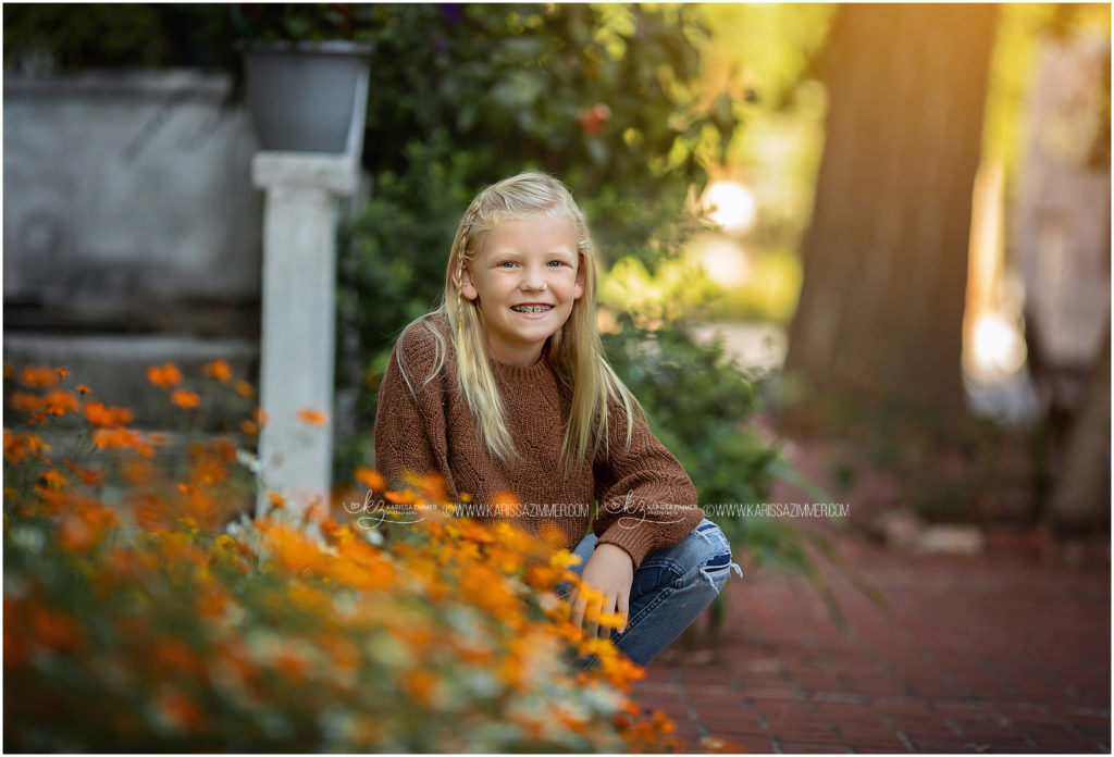 Young girl poses with some lingering fall flowers during her Harrisburg PA Fall Family Photography Session
