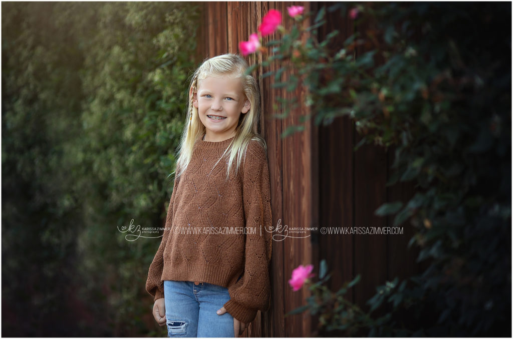 Young girl poses near flowers during her fall family photoshoot with Karissa Zimmer Photography
