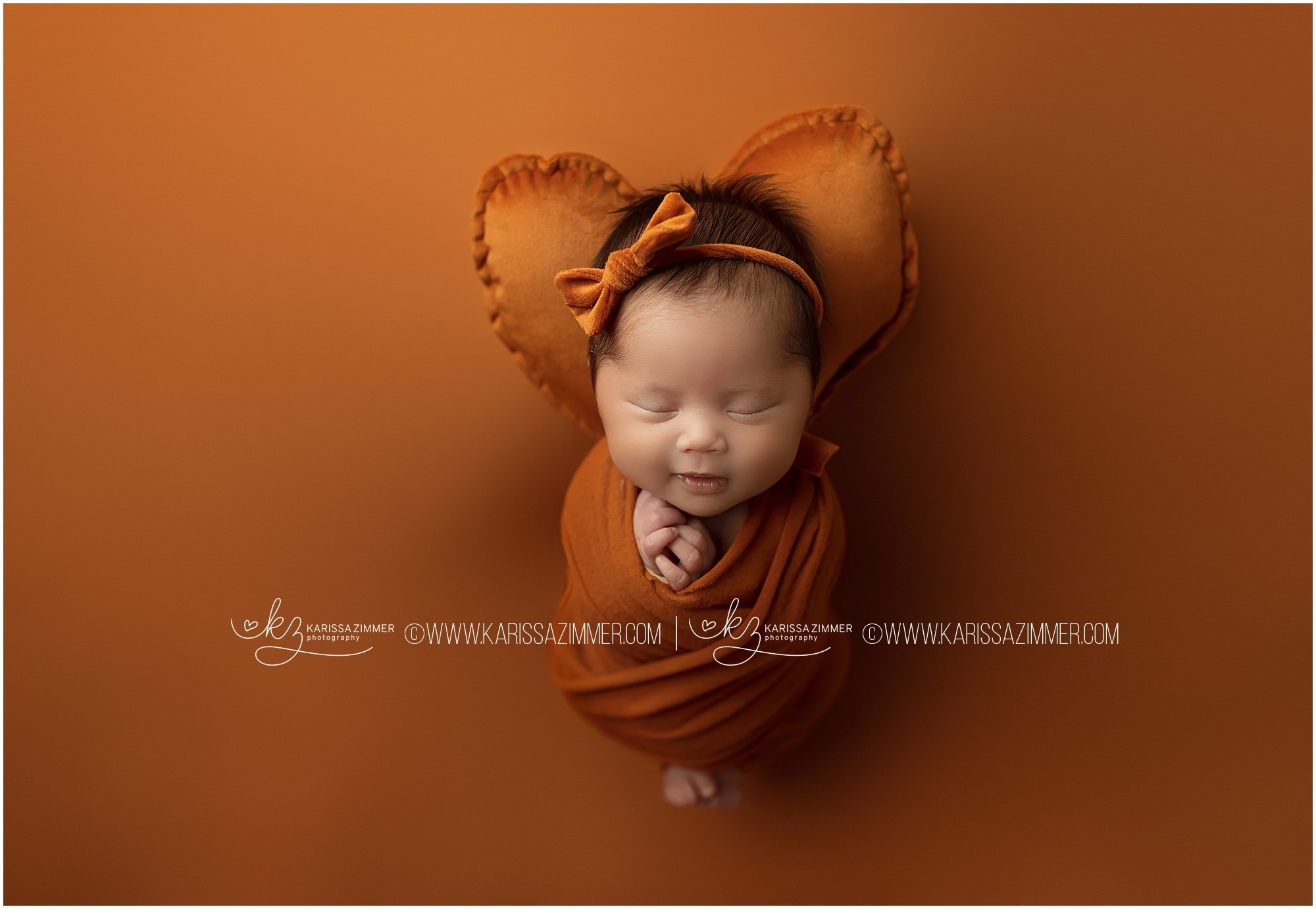 Newborn baby girl photographed on orange