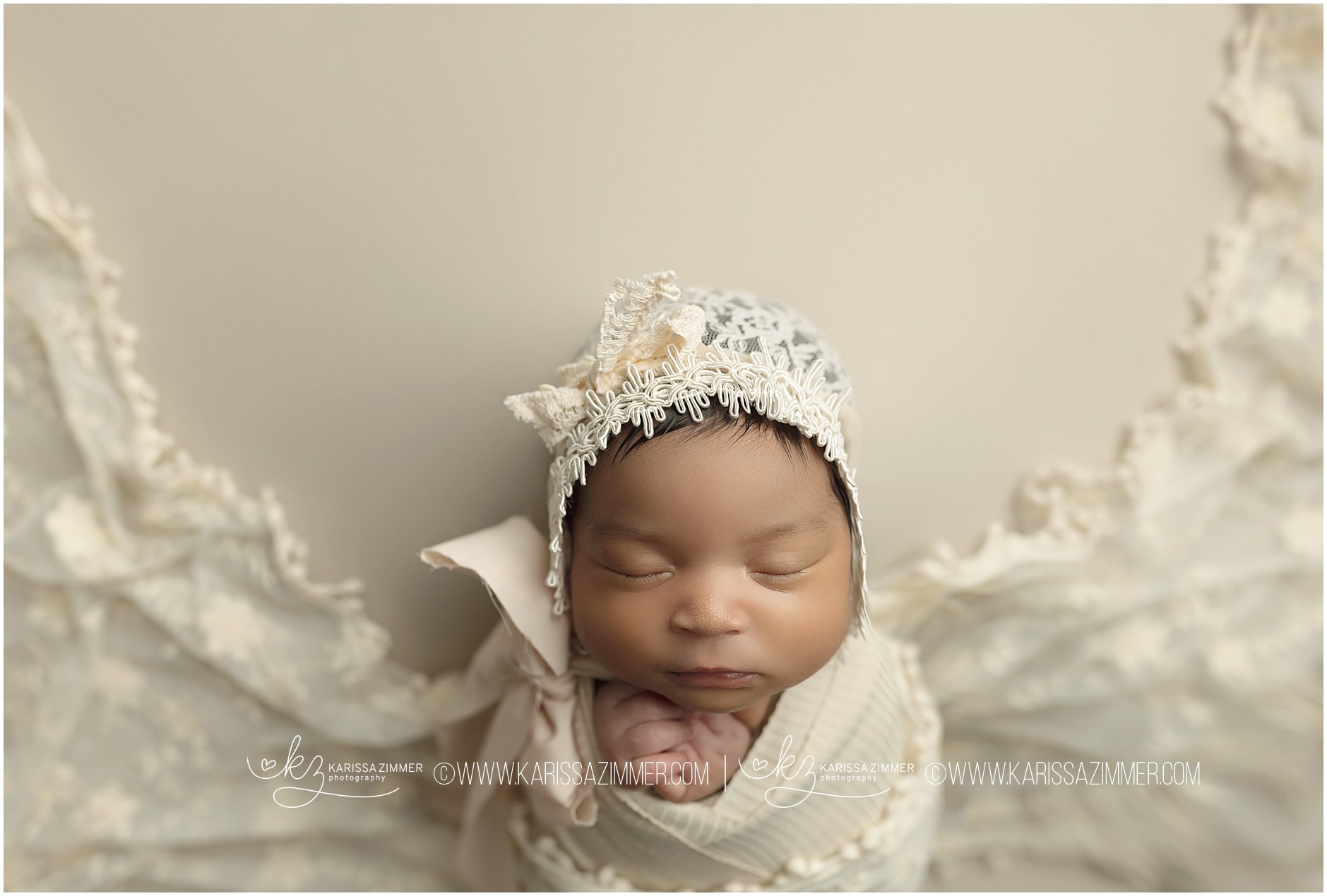 Newborn baby girl studio photo on cream backdrop with lace hat