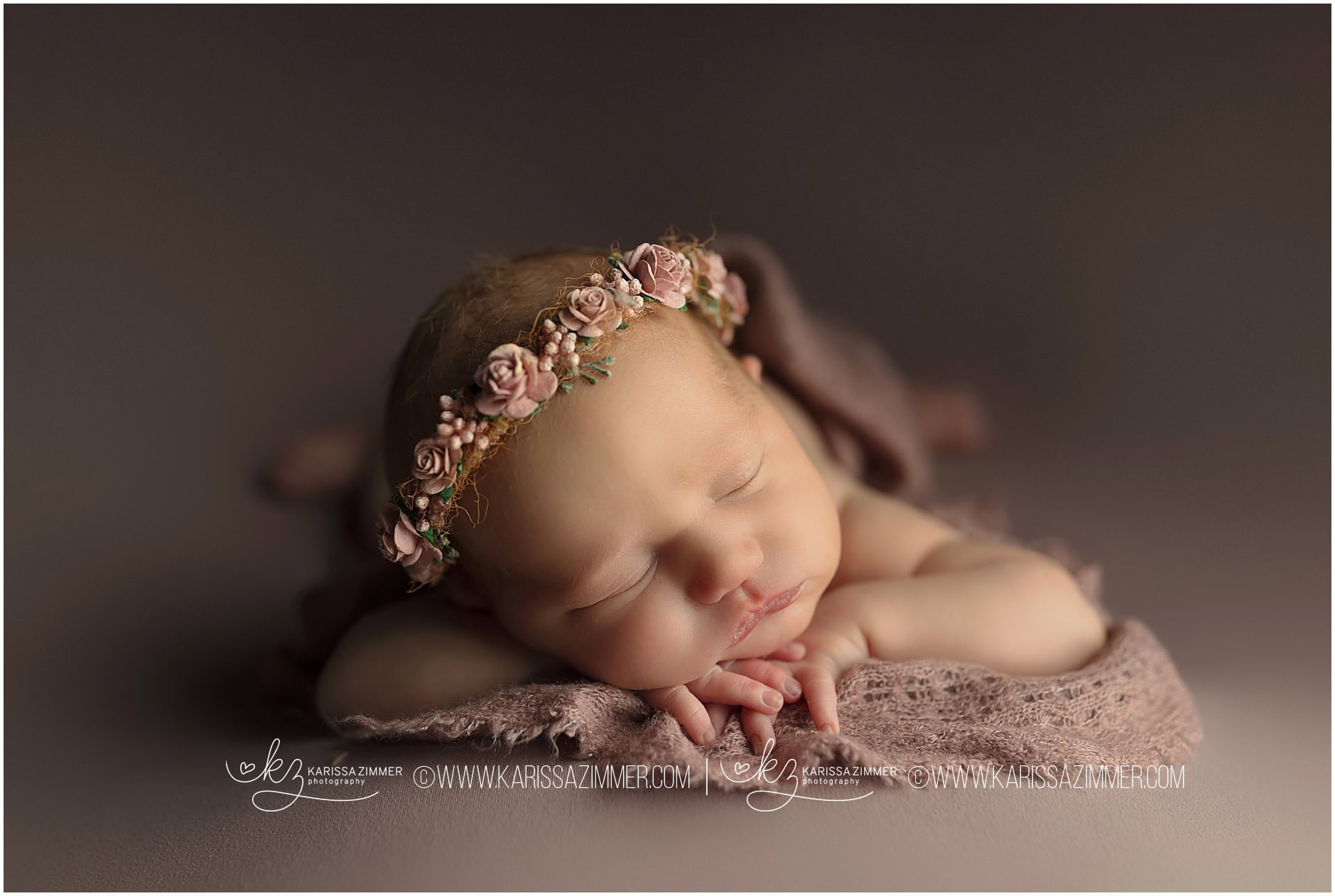 Studio newborn photography of baby girl posed on purple with flower crown. 