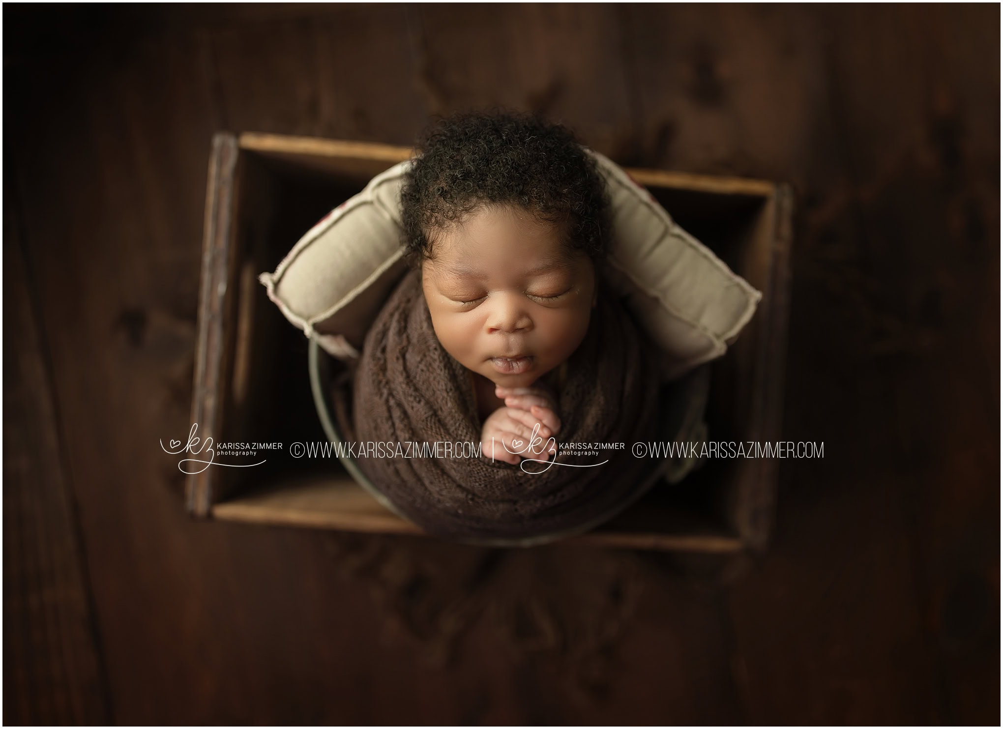 Newborn boy is wrapped and posed in a bucket prop and Photographed in Harrisburg Newborn Studio