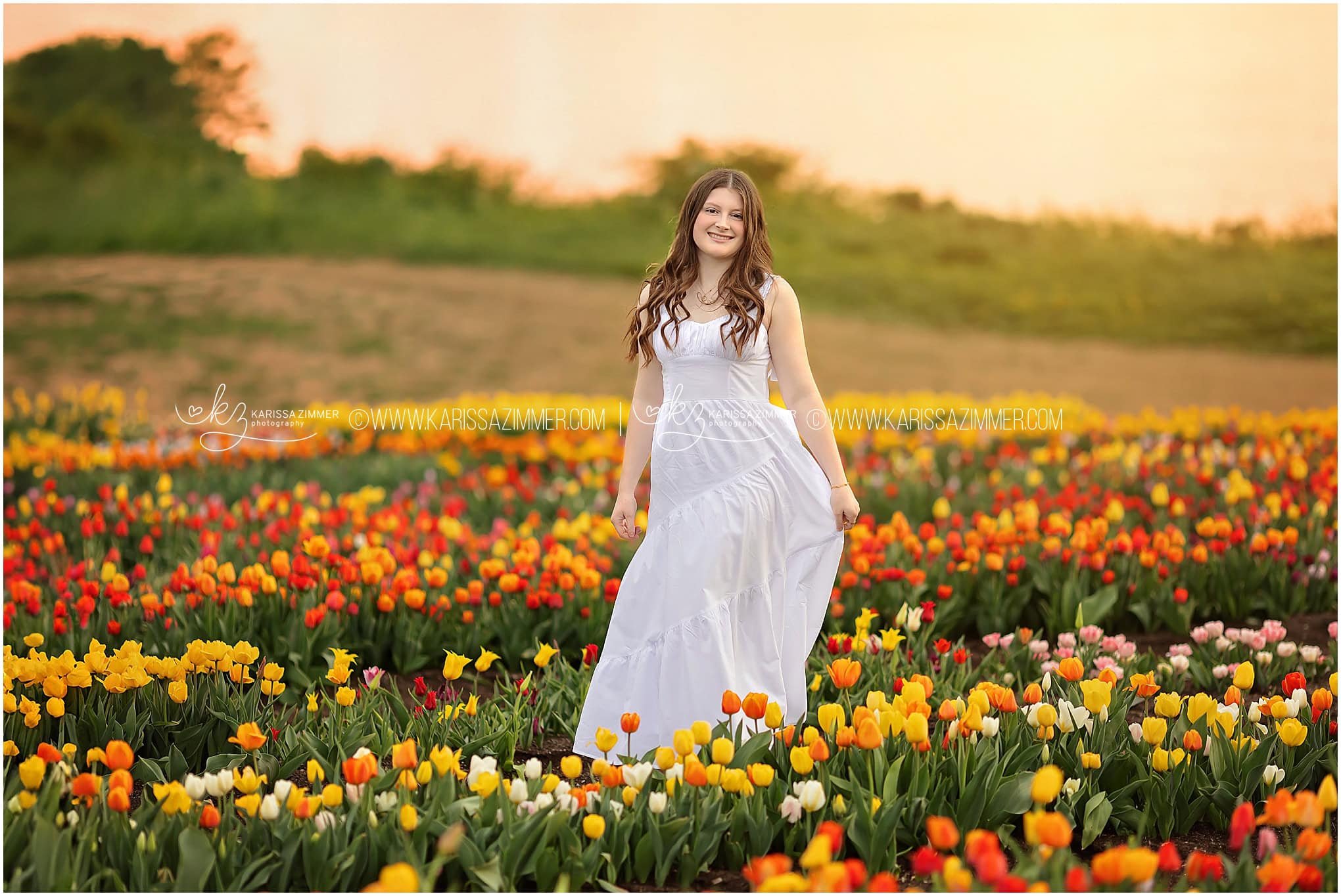 A high school senior girl spins in a tulip flower field during her senior photo session with best high school senior photographer, Karissa Zimmer Photography.