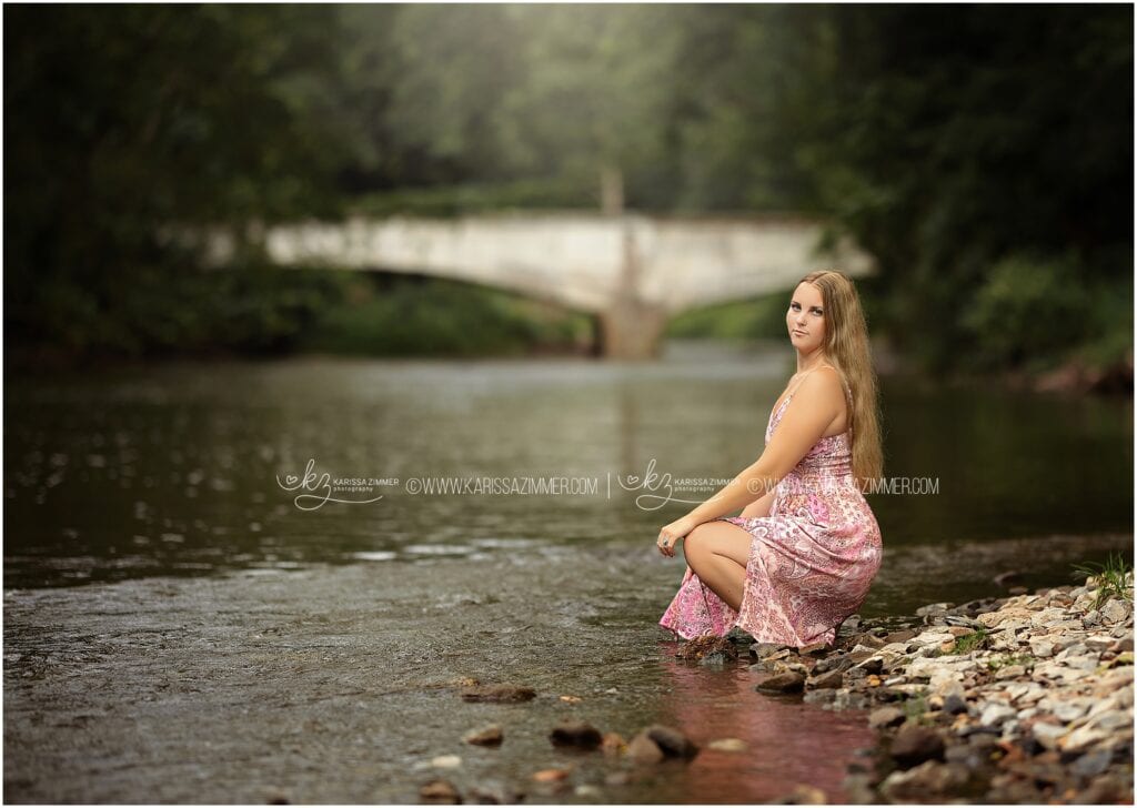 Girl Poses along a stony creekside for her high school senior pictures