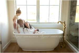 A new family of 4 interacts with one another while sitting in their soaker bathtub
