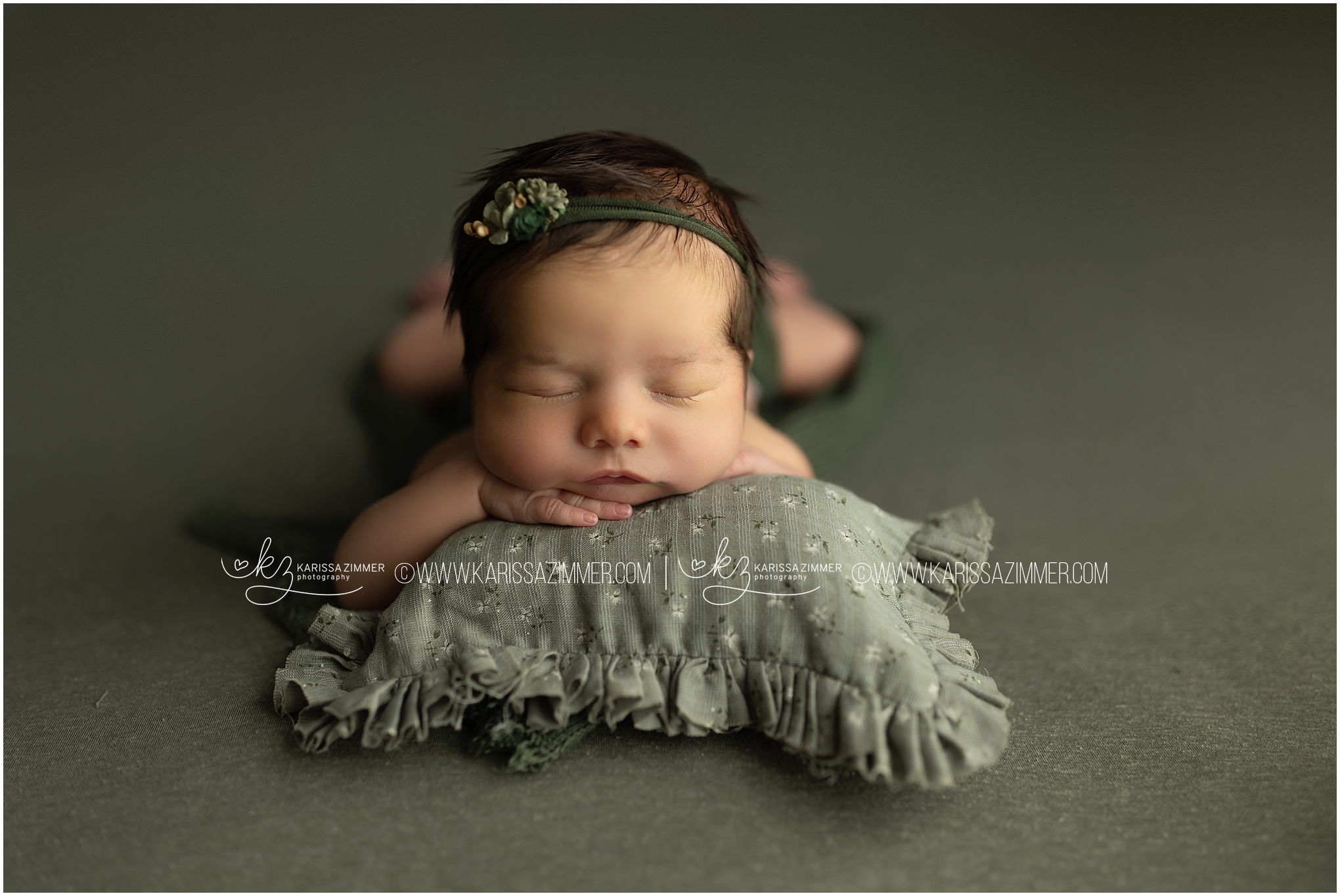 newborn baby girl posed on green setup, sleeps through her newborn photoshoot with Karissa Zimmer Photography