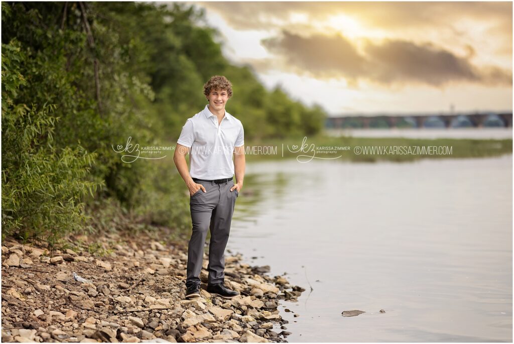 A high school senior boy stands by the river in Harrisburg for his senior portrait session